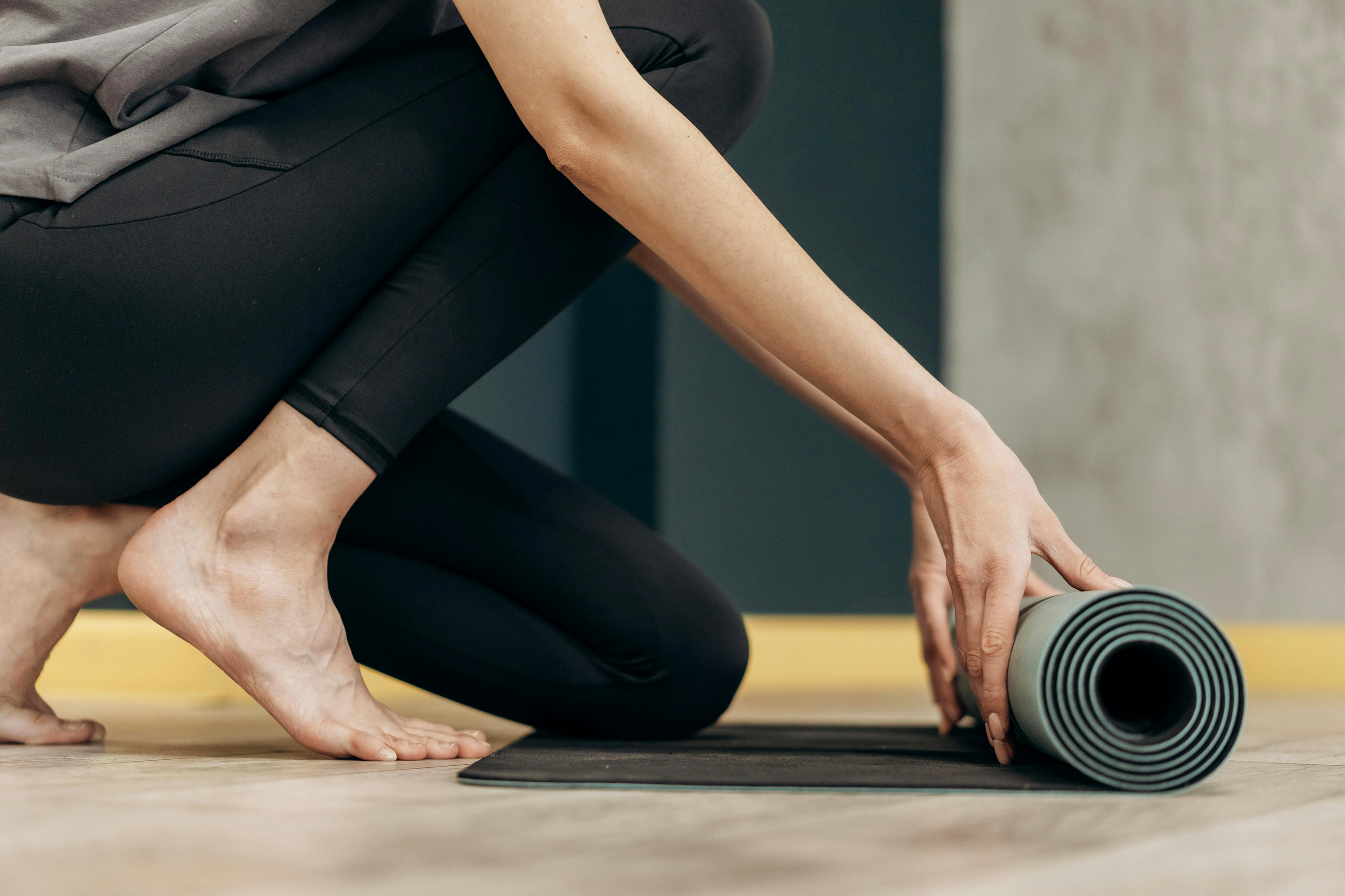 Woman rolling out mat, getting ready to exercise.